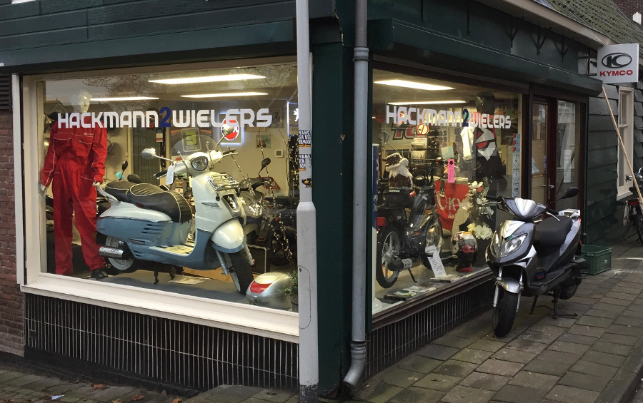 De etalage van Hackmann2wielers aan de Hogendijk in Zaandam, met scooters achter het glas